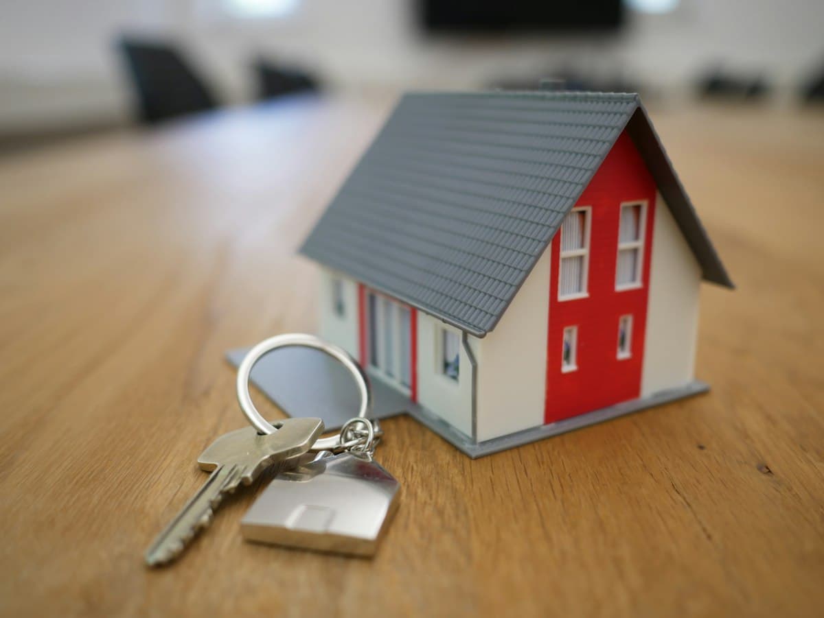 Manos entregando una maqueta de casa, compra y asesoría inmobiliaria